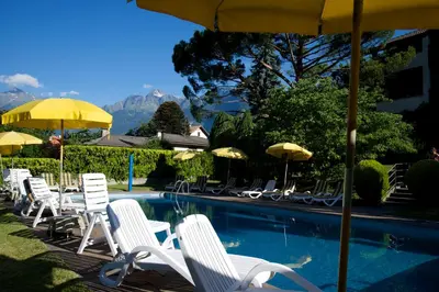 a group of chairs and umbrellas next to a pool at Hotel Tannerhof in Merano