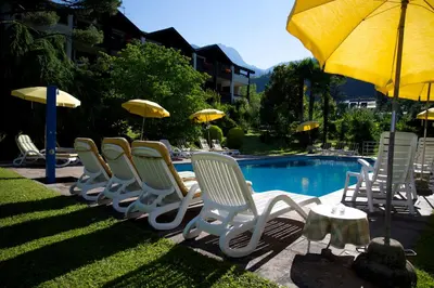 a row of chairs and umbrellas next to a pool at Hotel Tannerhof in Merano