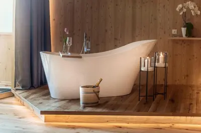 a bath tub sitting in a room with candles at Mountain Village Hasenegg in Schenna