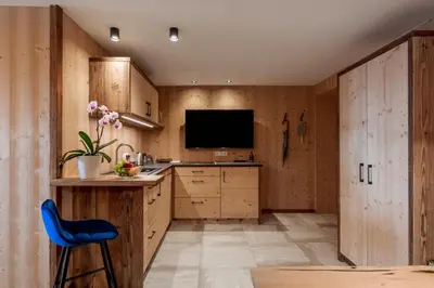 a kitchen with wooden cabinets and a blue chair at Mountain Village Hasenegg in Schenna