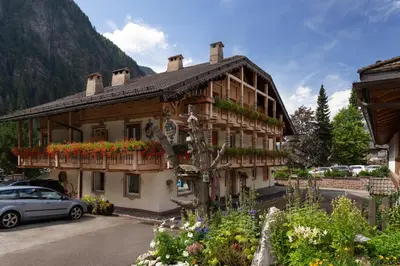 a building with flowers and a car parked in front of it at Appartamenti Ladina in Campitello di Fassa