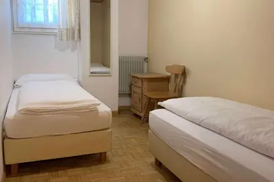 a small bedroom with two beds and a desk at Appartamenti Ladina in Campitello di Fassa