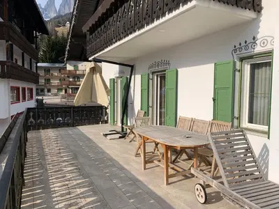 a wooden table and chairs on a patio at Appartamenti Ladina in Campitello di Fassa