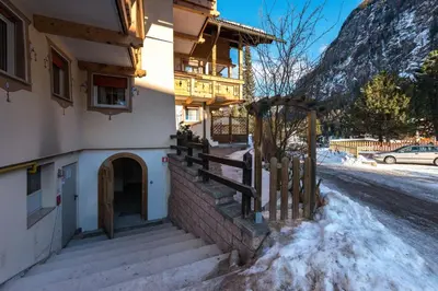 a house with a fence in the snow at Appartamenti Ladina in Campitello di Fassa