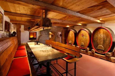 a dining room with a table and a bunch of wine barrels at MENA Guesthouse in Marlengo