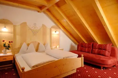 a bedroom with a bed and a red chair at Appartments Jägerhof in Valdaora