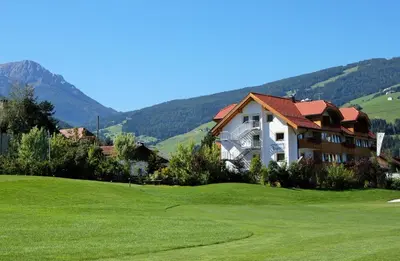 a house on a golf course with a green at Appartments Jägerhof in Valdaora