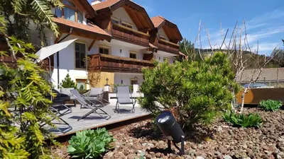 a house with a deck and chairs in the yard at Appartments Jägerhof in Valdaora