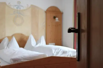 a bedroom with a bed with white sheets and pillows at Appartments Jägerhof in Valdaora