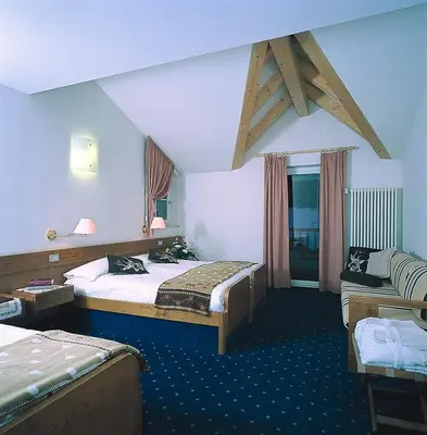 a hotel room with two beds and a couch at Piccolo Hotel in Canazei
