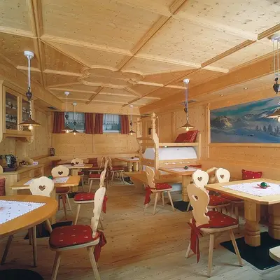 a room with tables and chairs and a piano at Piccolo Hotel in Canazei