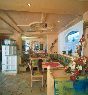 a living room with a table and chairs in a room at Piccolo Hotel in Canazei