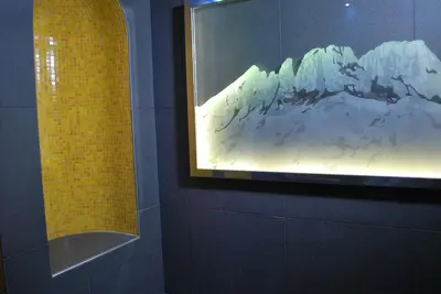 a painting of a mountain on a wall in a bathroom at Piccolo Hotel in Canazei