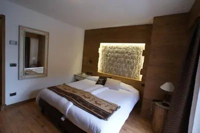 a bedroom with a large white bed with a mirror at Piccolo Hotel in Canazei