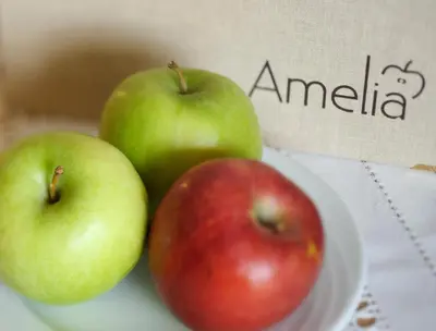 three apples sitting on a plate on a table at AMELIA apartments in Tirolo