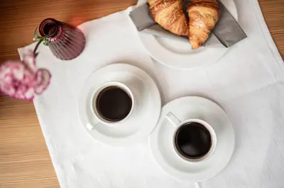 two cups of coffee and croissants on a table at AMELIA apartments in Tirolo