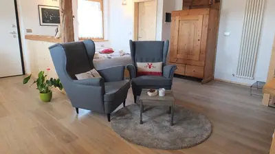 two chairs and a table in a room with a bed at Mini Maule in Cavalese