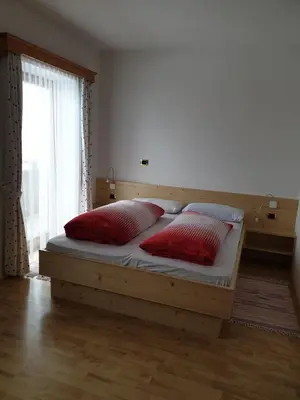a bedroom with a bed with two red pillows at Residence Alpenblick in Valles