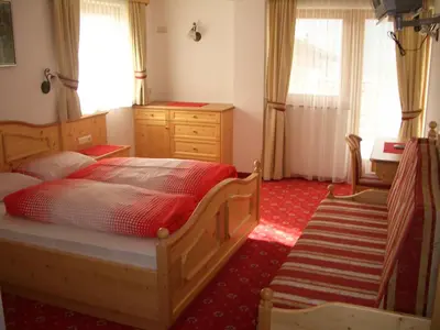 a bedroom with a bed and a dresser and windows at Residence Alpenblick in Valles