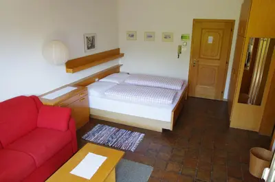 a small room with a bed and a red couch at Appartements Oberpefohl in Parcines