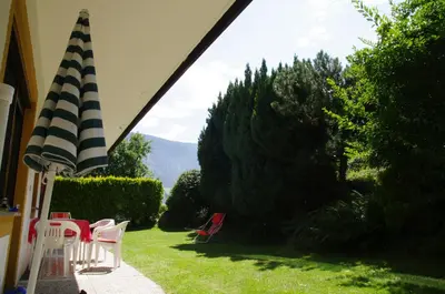 a view of a lawn with chairs and an umbrella at Appartements Oberpefohl in Parcines