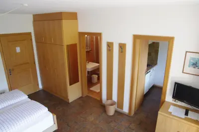 a bedroom with a bed and a television and a bathroom at Appartements Oberpefohl in Parcines