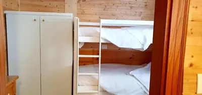 a room with a bunk bed with white sheets at Appartamento Pampeago 10 in Tesero