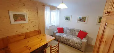 a living room with a couch with two red pillows at Appartamento Pampeago 10 in Tesero