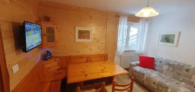 a living room with a television and a wooden wall at Appartamento Pampeago 10 in Tesero