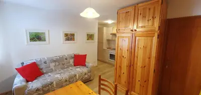 a living room with a couch and a kitchen at Appartamento Pampeago 10 in Tesero