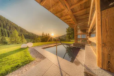 a view of a house with a pond in the yard at Hotel Comploj Adults only in Selva di Val Gardena
