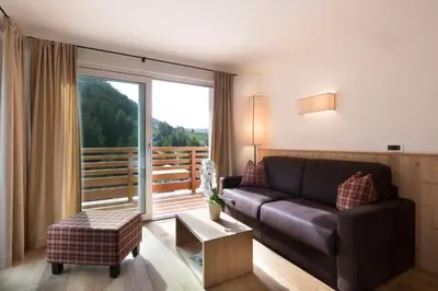 a living room with a couch and a large window at Hotel Comploj Adults only in Selva di Val Gardena