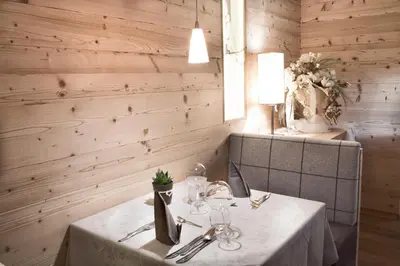 a dining room with a table with glasses and flowers at Hotel Comploj Adults only in Selva di Val Gardena