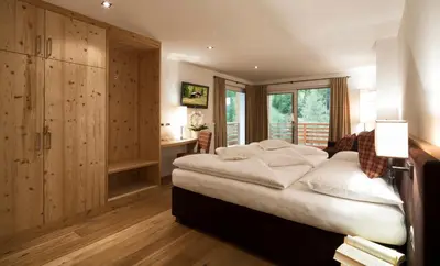 a bedroom with a large bed and a large window at Hotel Comploj Adults only in Selva di Val Gardena