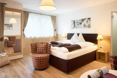 a bedroom with a bed and a chair at Hotel Comploj Adults only in Selva di Val Gardena