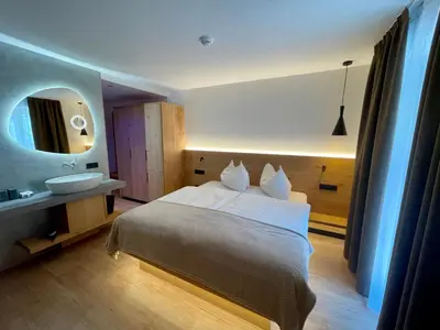 a bedroom with a bed and a sink and a mirror at Hotel Des Alpes in Selva di Val Gardena
