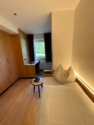 a room with a bed and a table in it at Hotel Des Alpes in Selva di Val Gardena