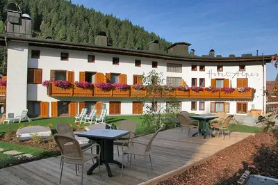 a large building with tables and chairs in front of it at Hotel Des Alpes in Selva di Val Gardena