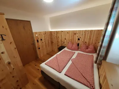 a bedroom with a bed in a room with wooden walls at Hörmannhof in Bressanone