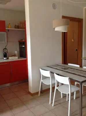 a kitchen with a table and white chairs in a room at HOME DI CRISTINA in Laives