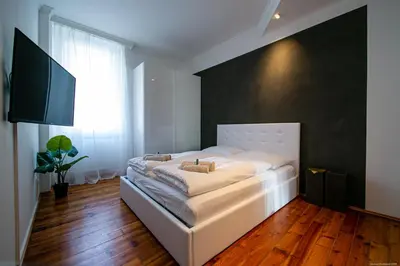 a bedroom with a white bed with a black wall at Apartment Andreas in Bolzano
