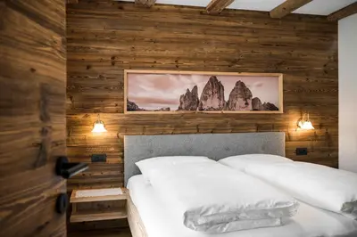 a bedroom with wooden walls and a bed with white pillows at Chalet Dolomit in San Lorenzo di Sebato