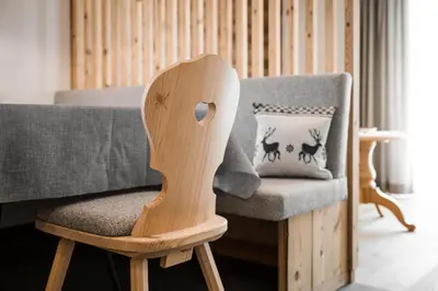 a wooden chair next to a couch with a pillow at Chalet Dolomit in San Lorenzo di Sebato
