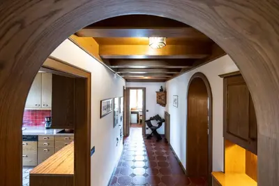 an archway leads into a kitchen with white walls and wooden ceilings at Apartments Sayonara in Castelrotto