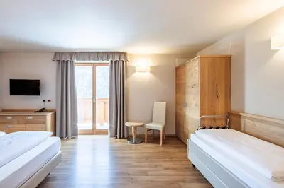 a hotel room with two beds and a tv at Albergo Belvedere in Vigo di Fassa