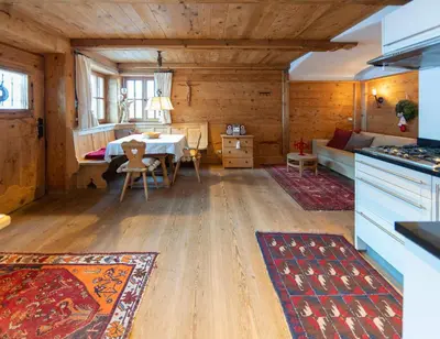 a kitchen and living room with a table in a cabin at Villa al Bosco in Selva di Val Gardena