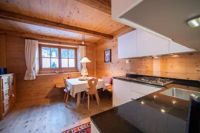 a kitchen and dining room with a table in a cabin at Villa al Bosco in Selva di Val Gardena
