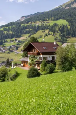 a house on a hill in a field of grass at Villa al Bosco in Selva di Val Gardena