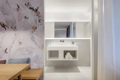 a bathroom with a white sink and a table at Cityflair Boutique Apartments in Bolzano