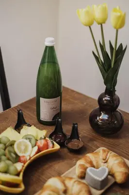 a table with a bottle of wine and a plate of food at Töllhof Apartments and Farm in Naz-Sciaves